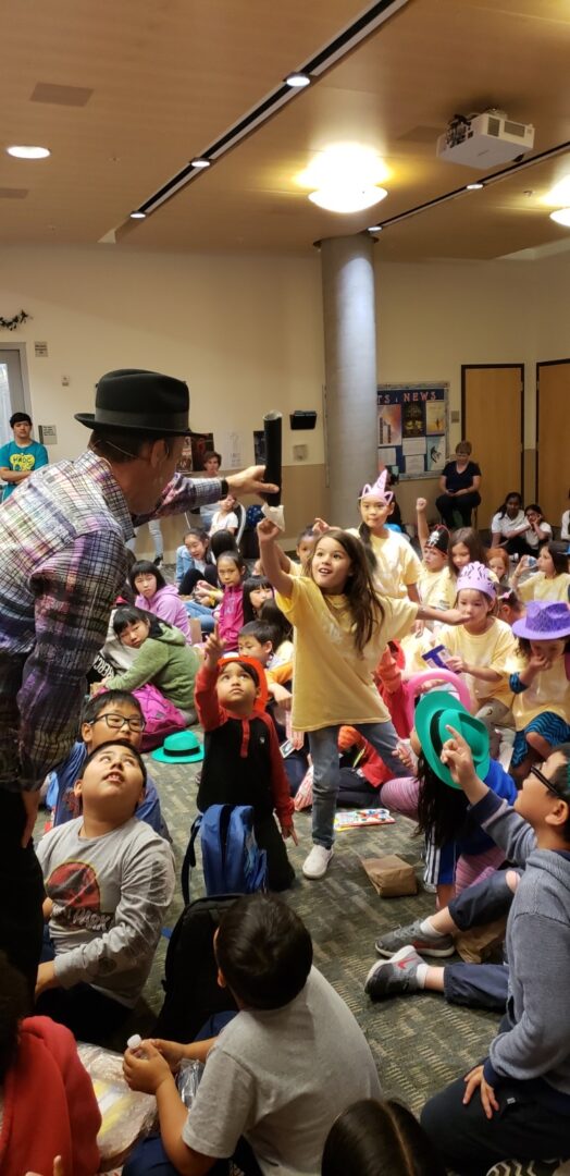 A man in a hat is holding up something to the children.