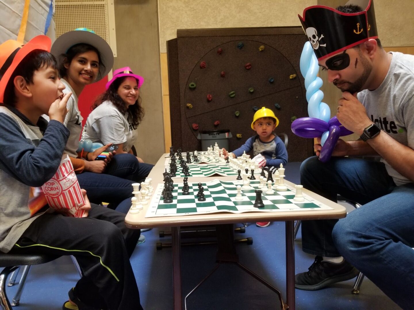 A group of people sitting around a table with chess pieces.