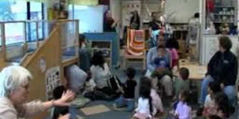 A group of children sitting on the floor in front of a screen.