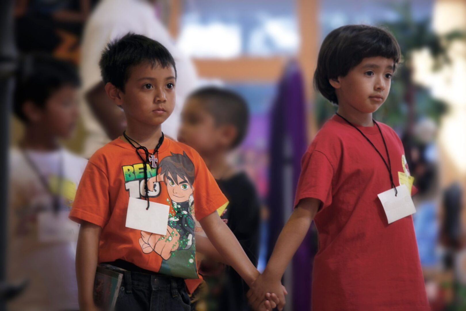 Two children holding hands while standing in a room.